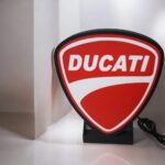 Dépôt de marque célèbre Ducati en version lumineuse 3D, lampe LED décorative en forme de bouclier avec logo rouge et blanc, éclairage innovant pour fans de moto et décoration intérieure.