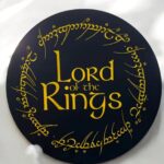 Lemballage lumineux en 3D avec le texte "Lord of the Rings" entouré d'écriture elfique dorée sur un fond noir, créant une décoration unique et élégante pour les fans de la saga.