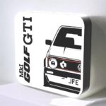 Logo lumineux de la marque GOLF, avec une illustration stylisée d'une voiture VW Golf, conçue en impression 3D LED pour une décoration intérieure moderne et personnalisée.