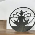 Silhouette en métal noire représentant une figure de méditation en position lotus avec un fond mandala, création lumineuse 3D LED.