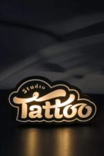 Lampe LED en forme de logo Studio Tatto, éclairée pour un effet lumineux, création personnalisée en impression 3D, décoration artistique, ambiance chaleureuse, design moderne et original.