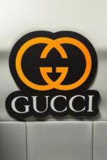 Gucci logo en 3D lumineux avec LED orange et noir, création personnalisée pour décoration intérieure ou accessoires de mode.