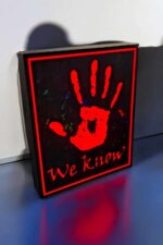 Un panneau lumineux en noir avec une main rouge illuminée, texte "We Know" en dessous, créant une ambiance design et moderne.