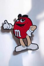 M&M's personnage lumineux en 3D avec une expression confiante, design coloré et amusant, idéal comme décoration ou lampe LED innovante, créée par Infinity 3D Print.