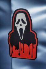 Un sticker 3D personnalisé représentant une figure avec un masque de Scream, fabriqué avec impression 3D, idéal pour la décoration lumineuse et originale.