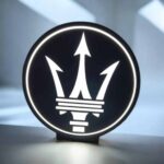 Une lampe LED 3D illuminée avec logo Maserati, conçue par Infinity 3D Print, alliant design moderne et éclairage lumineux pour une décoration intérieure élégante.