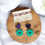 Des boucles d'oreilles colorées en forme de coeurs et de fleurs en bois, montées sur des crochets en métal or, présentées sur une carte de branding élégante, parfaites pour un style unique et artisanal.