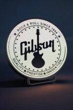 Lampe LED design vintage Gibson avec logo lumineux blanc et noir, idéale pour décoration intérieure, ambiance musicale rétro.