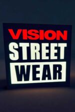 Vitrine lumineuse LED affichant le message "VISION STREET WEAR" avec éclairage en flip-flop rouge, blanc et noir, idéale pour décoration intérieure ou publicité vintage.