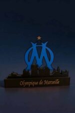 Étiquette alt : Lampe LED en 3D représentant le logo de l'Olympique de Marseille avec un fond sombre et un éclairage bleu lumineux.