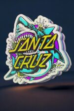 Vitrine d'une création lumineuse 3D représentant un grand requin avec le texte "Santa Cruz" en couleurs vives, fabriquée par Infinity 3D Print, idéale pour décoration originale et moderne.