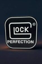 Logo GLOCK lumineux 3D avec inscription "PERFECTION" sur fond noir, idéal pour décoration ou collection.