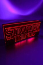 Lampe LED en 3D affichant le logo "Stranger Things" illuminé en rouge avec un fond violet.