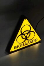 Warning biohazard sign illuminated LED lamp, glow-in-the-dark biotechnological safety symbol, modern 3D printed luminous artwork, decorative lighting for laboratories or science events, innovative home or office décor piece.