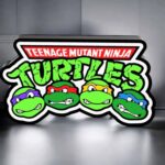 Colorful Teenage Mutant Ninja Turtles LED lamp with vibrant turtle faces and bold lettering, ideal for illumination and decoration.