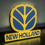 Lumière 3D personnalisée représentant un logo avec texte "NEW HOLLAND" en LED, créant un effet lumineux coloré pour décoration ou signalétique.